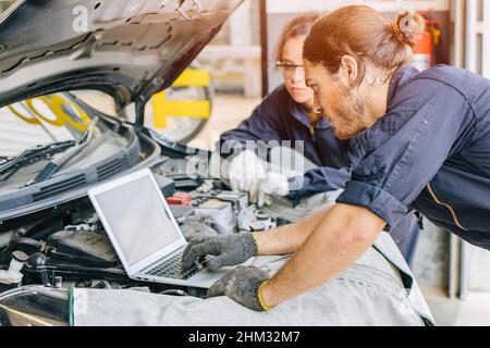 Meachnic staff worker using laptop computer check ane tuning car engine in garage Stock Photo