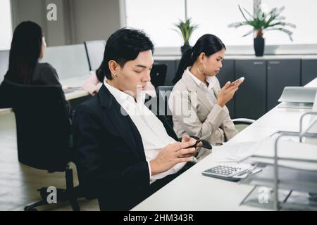 Office employee playing smartphone at work and social media addicted bad habit for business company problem. Stock Photo