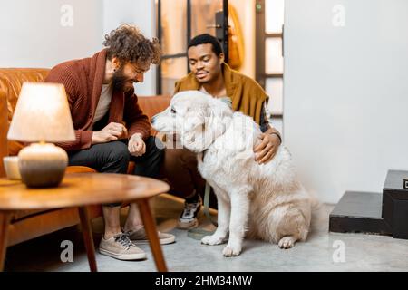 Gay couple having fun with a dog at home Stock Photo