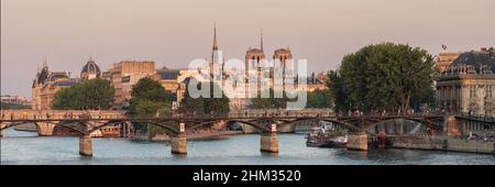 PARIS, FRANCE - AUGUST 2018:  Panorama view along the River Seine toward Pont des Arts, Pont Neuf and  and the Notre-Dame Cathedral in golden light