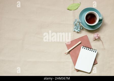 Notepad and cup of coffee on beige fabric background. top view, copy space Stock Photo