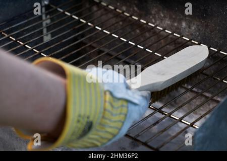 With wire brush clean dirty grill rust. Protect gloves. Stock Photo