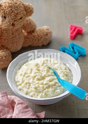 bowl of baby food. rice and milk pudding on wooden kitchen table Stock Photo