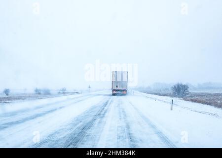 Freight transportation truck on the road in snow storm blizzard, bad weather conditions for transportation event, selective focus Stock Photo