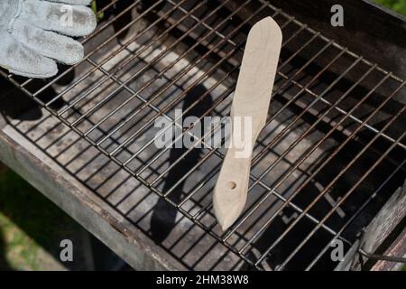 Wire brush and protective hand glove on dirty grill rust. Tool casts dark shadow. Oblique from above. Stock Photo