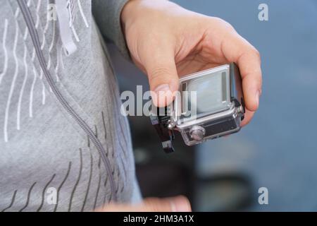 A man holds in his hands and looks through the footage on an action camera Stock Photo