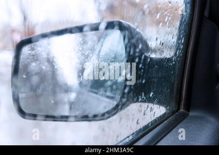 View of the rear view mirror on a rainy day from inside the car. Blurred view Stock Photo