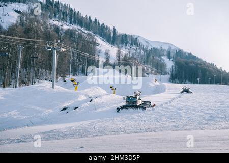Snowcat ratrack with snowplow snow grooming machine preparing ski slope piste hillalpine skiing winter resort Rosa Khutor. Stock Photo