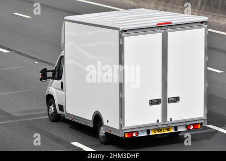 Back side & aerial view of square shape all white clean box van with back doors built onto a white standard chassis cab vehicle on UK motorway road Stock Photo