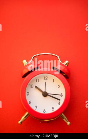 new red round clock on red table, side view. Stock Photo