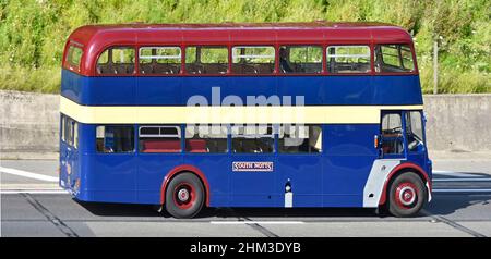 South Notts Bus company side view, historical old double decker bus with two passengers and driver driving along on UK motorway road in Essex England Stock Photo