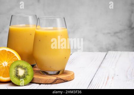 Glass of green banana, orange and kiwi healthy smoothies. Stock Photo