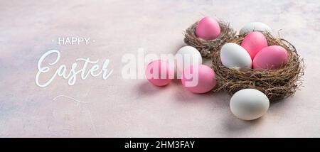 Pink and white Easter eggs in a nest and on a light pink background. The concept of a Happy Easter. Side view. Stock Photo