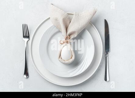 Serving the Easter table. Easter bunny made of napkins and eggs on plates. Top view. The concept of a Happy Easter. Stock Photo