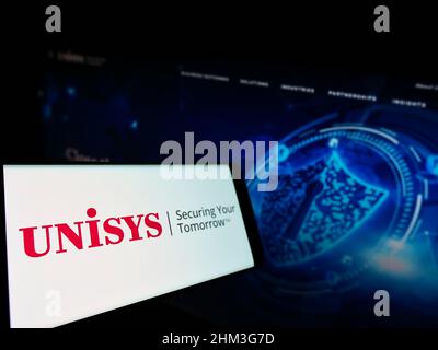 Smartphone with logo of American IT company Unisys Corporation on screen in front of business website. Focus on center-left of phone display. Stock Photo