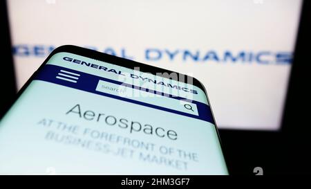 Smartphone with webpage of American company General Dynamics Corporation (GD) on screen in front of logo. Focus on top-left of phone display. Stock Photo