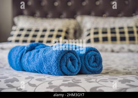 Freshly laundered fluffy towels on bed in hotel Stock Photo