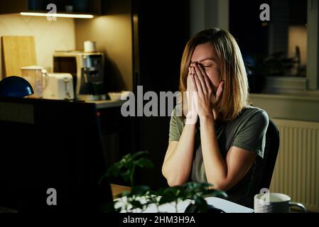 Tired woman works from home use computer at night, overwork burnout, freelancer works remote at home workplace Stock Photo