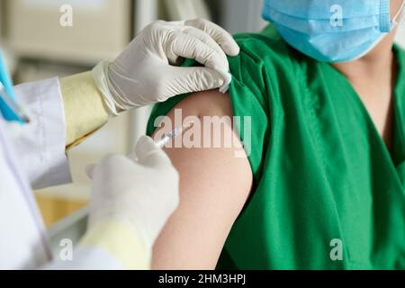 Close-up image of doctor making injection of vaccine in shoulder of medical nurse Stock Photo