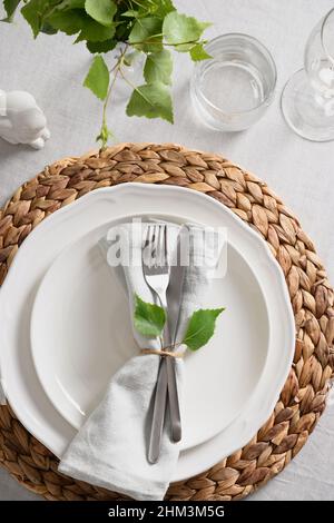 Easter elegant table setting with bunny, fresh greens on white linen tablecloth. View from above. Christian religion tradition. Stock Photo