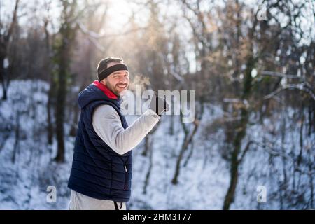 Adult man is ready for exercising in park in wintertime. He is smiling and showing thumb up. Stock Photo