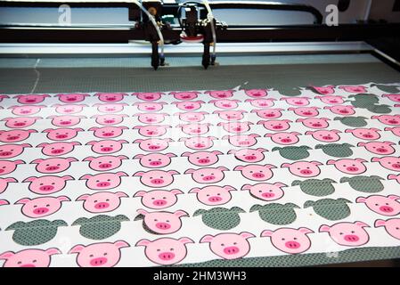 Drawings of piglets on the fabric on the machine for cutting Stock Photo