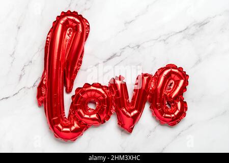 inflatable letters love in red color isolated on marble background Flat lay Top view Holiday card, Happy Valentines day concept Love in air Stock Photo