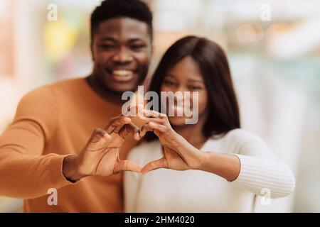 Happy smiling black couple making heart shape with hands Stock Photo