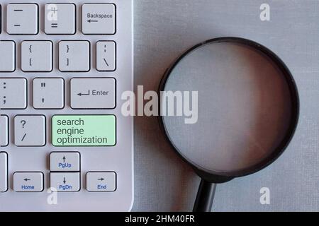 Search engine optimization or SEO concept. Top view image of magnifying glass and keyboard. Stock Photo