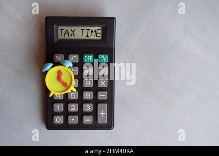 Top view image of alarm clock and calculator with text TAX TIME on display. Copy space for text Stock Photo