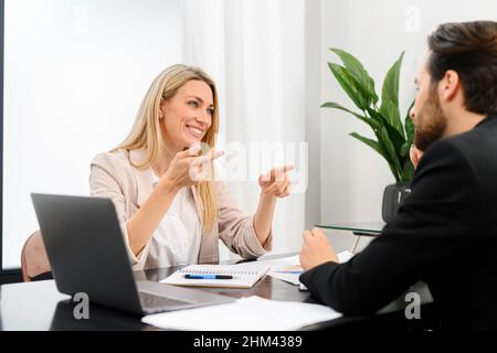 Going over details. Male and female confident business people discussing something while spending time in the office. Male office worker looking at his colleague while discussing something Stock Photo