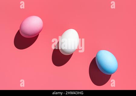 Three Easter eggs of different colors on a pink background. Abstract Easter background. Stock Photo