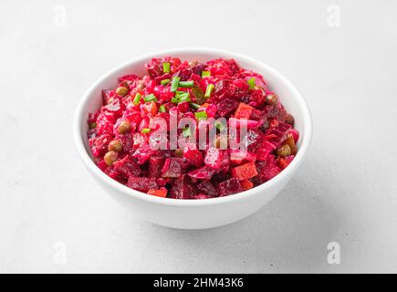 Salad vinaigrette with boiled vegetables, sauerkraut, cucumbers and peas on a light background. Side view. Stock Photo