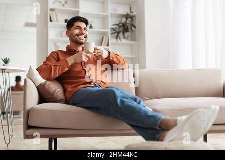 Man having rest at home on the couch, drinking coffee Stock Photo