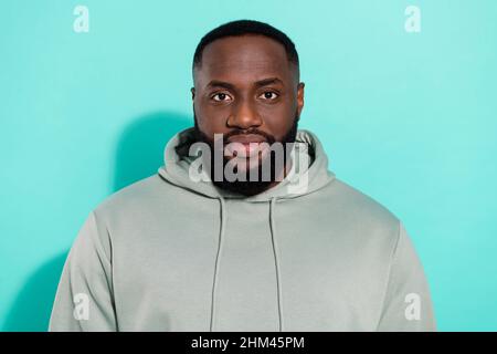 Portrait of attractive content guy wearing hood plump lips isolated over vibrant teal turquoise color background Stock Photo