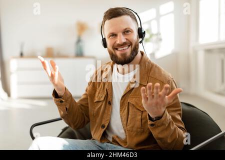 Cheerful Male Freelancer Making Video Call Wearing Headset At Home Stock Photo