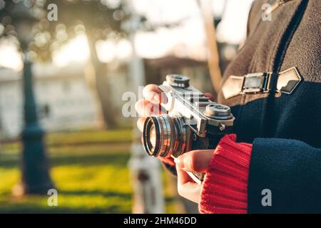 Close up shot of woman hand holding retro camera in forest at sunny weather. Stock Photo