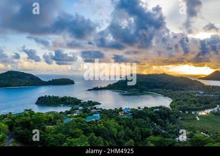 Mahe Island coast drone sunset landscape with dramatic sky, clouds, lush tropical forest and small islands around. Stock Photo