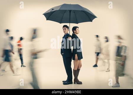 Business men and women with an umbrella stand in the crowd Stock Photo