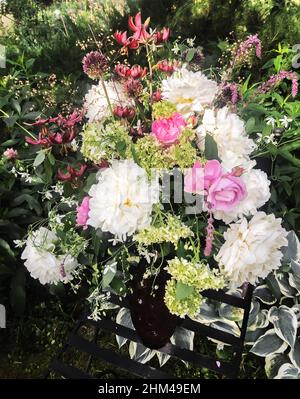 Romantic bouquet with peonies, roses, hydrangea, lily martagon, allium, geyhera and sage. Summer bouquets of farm flowers outdoors in the garden. Flor Stock Photo