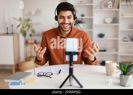 Arab man having videocall using cellphone on tripod and talking Stock Photo