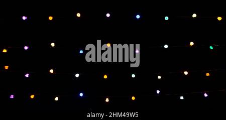 Multicolored light bulbs on dark hight sky background. Blurred focus. Banner. Stock Photo