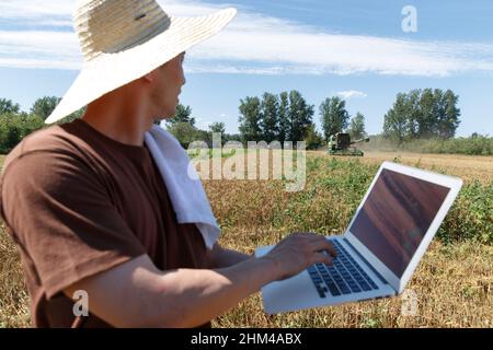 Researchers stood beside the wheat field using a computer Stock Photo