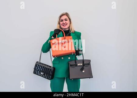 London 08 Feb 2022 Model holding (R) Orange H Ostrich  Birking 30 Hermès, 2002, estimate £8,000 – 12,000 and Black aged patent Leather Reissue Double Flap Bag Chanel, 2010-2011, a ‘re-issue’ flap bag, which has the original turnlock fastening designed by Chanel in 1955, £2,500 – 3,500,(L)A Special order bicolour Etain and Black Togo Birking 30 Hermes, 2018 estimate £7,000 – 10,000.Paul Quezada-Neiman/Alamy Live News Stock Photo