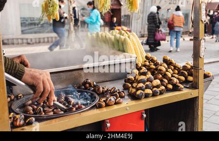 Street seller roasting chestnuts, a popular autumn and winter street food in Istanbul, Turkey, Stock Photo