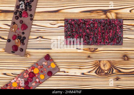 different kinds of chocolate with dried fruits on a wooden board Stock Photo