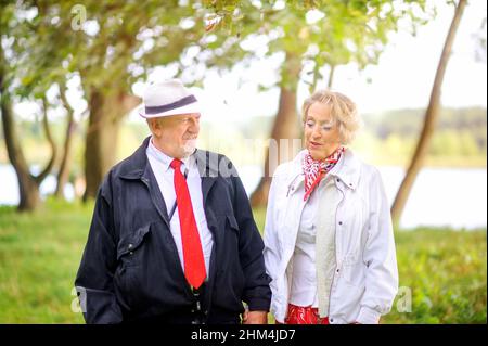 happy elderly couple walking in the park at sunset Stock Photo