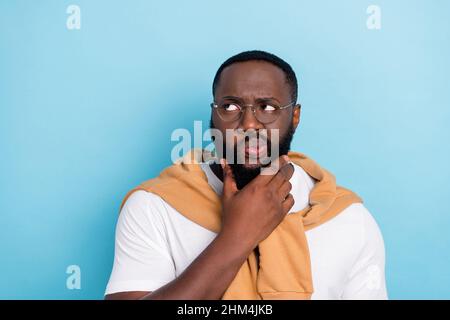 Portrait of young man grumpy face imagine brainstorming look copyspace isolated on blue color background Stock Photo