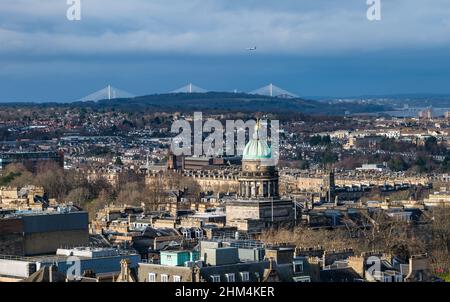 Edinburgh, Scotland, UK, 7th February 2022. UK Weather: sunshine and showers. The capital city lights up in the sunshine with a showery dark sky behind the Queensferry Crossing bridge in the distance with the copper dome of West Register House prominent in the city landscape Stock Photo