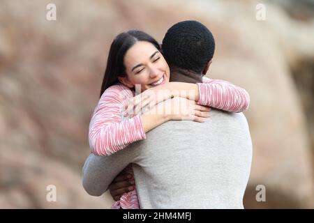 Happy affectionate woman hugging a man outdoors in a date Stock Photo